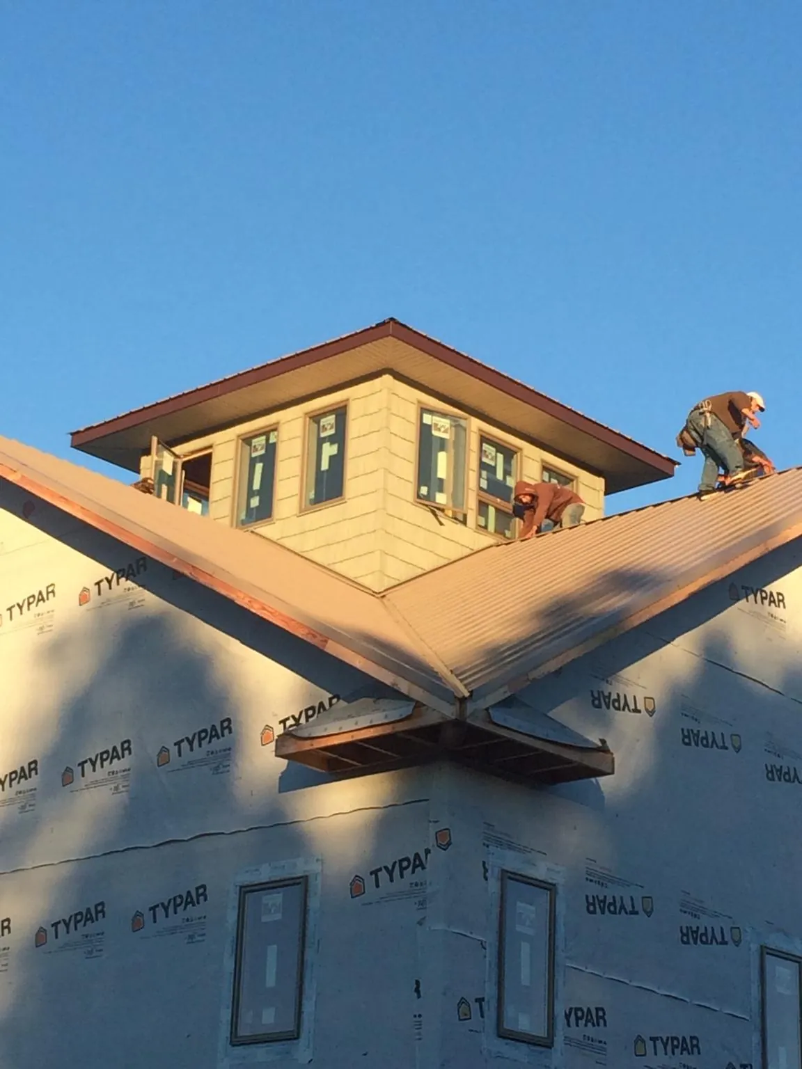 Roofers working around a rooftop cupola on a new metal roof at sunset — Roof Waterproofing in Lyons by Roofing Brothers
